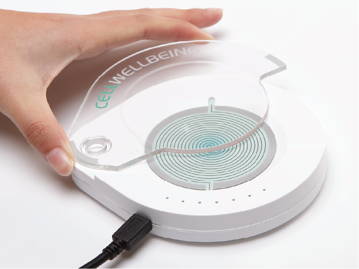 A hand lifting off a transparent plastic cover of the Cell Wellbeing S-Drive while it is being plugged into a power cord.
