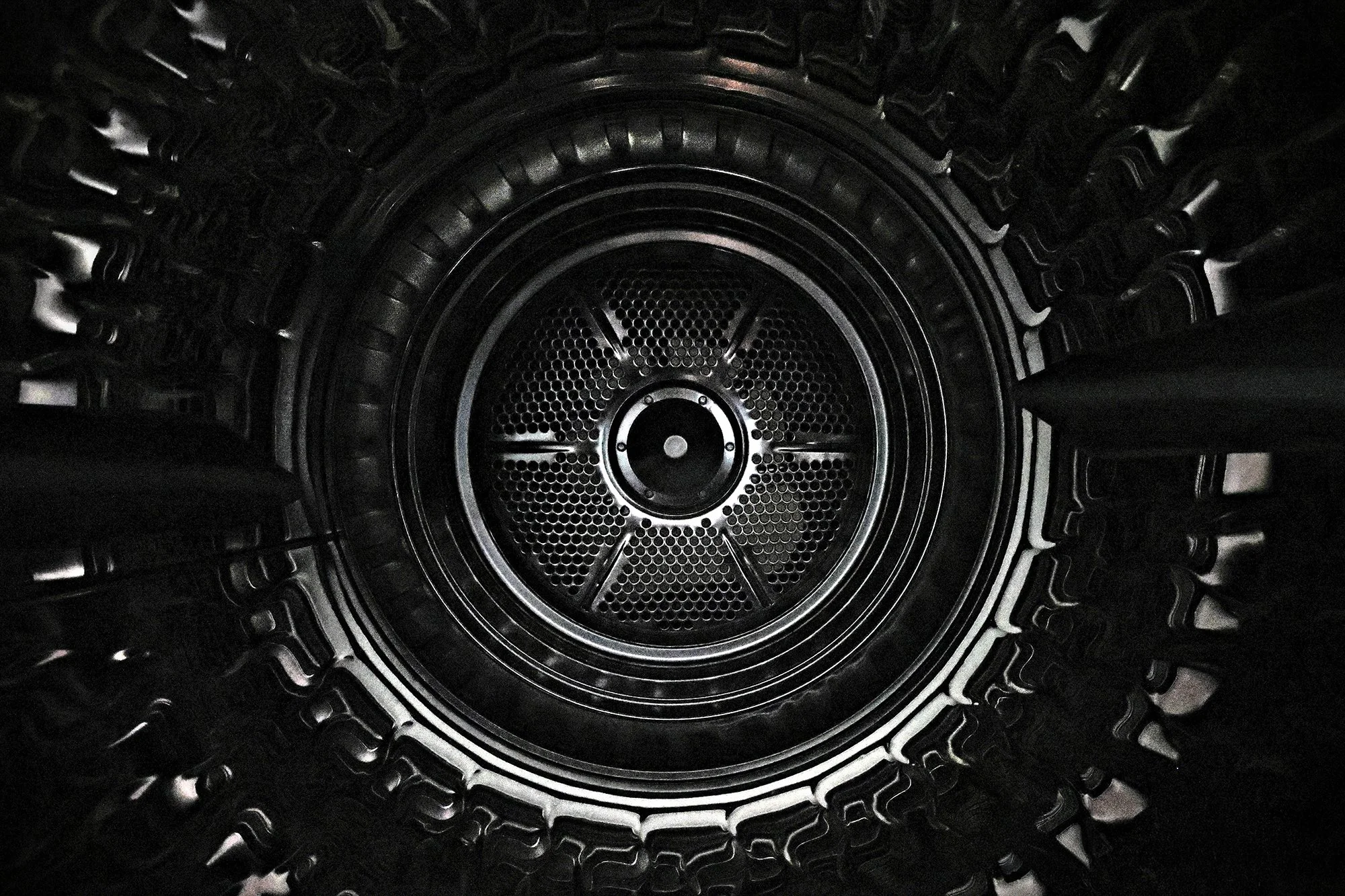 Close-up of a black tire viewed from the center, showing the tread pattern and sidewall details.