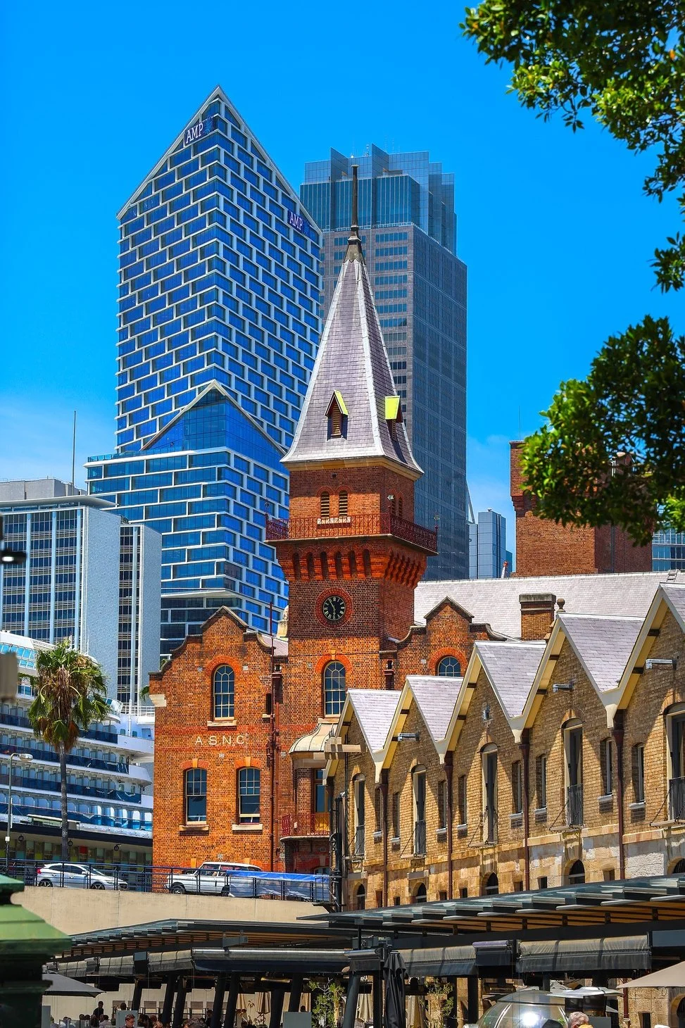 A historic brick church with a tall steeple and clock tower in front of modern skyscrapers in a cityscape.