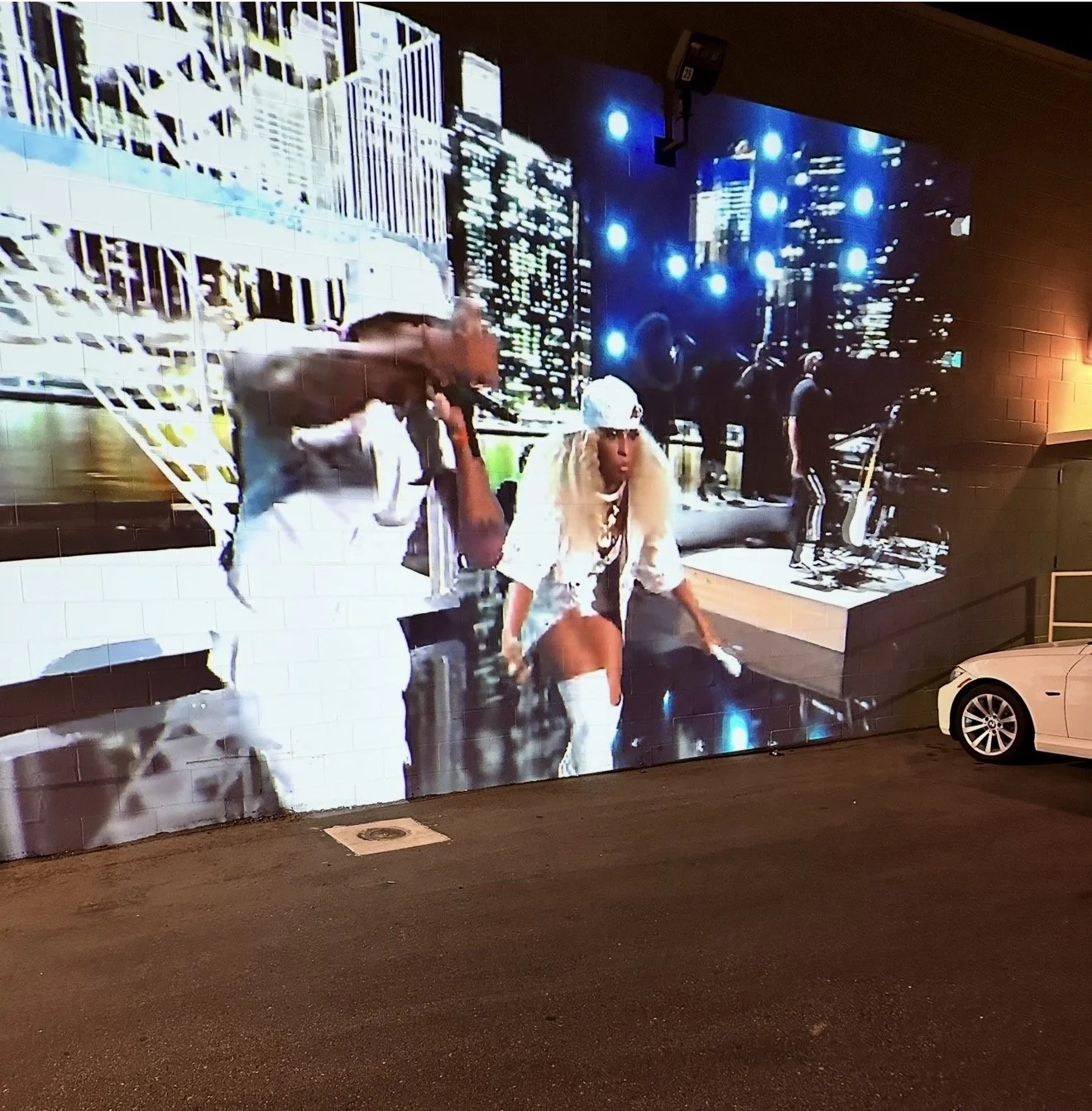 Large billboard displaying a distorted image of people on a city street at night.