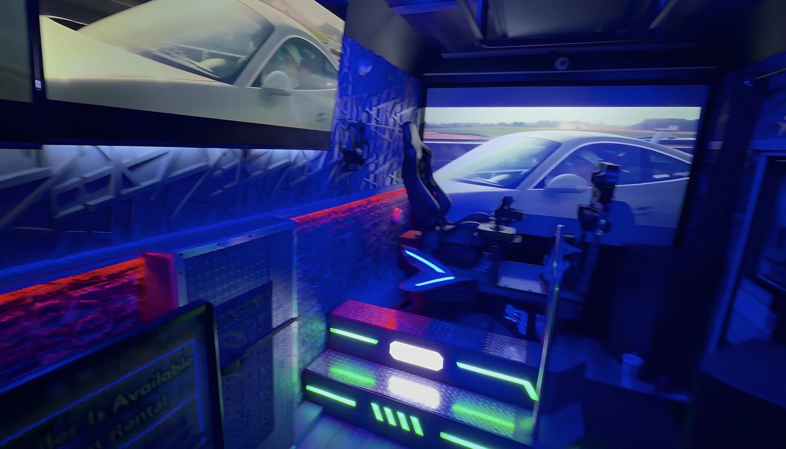 Inside a flight simulator with multiple screens displaying an airplane view, with gaming chairs and illuminated panels.