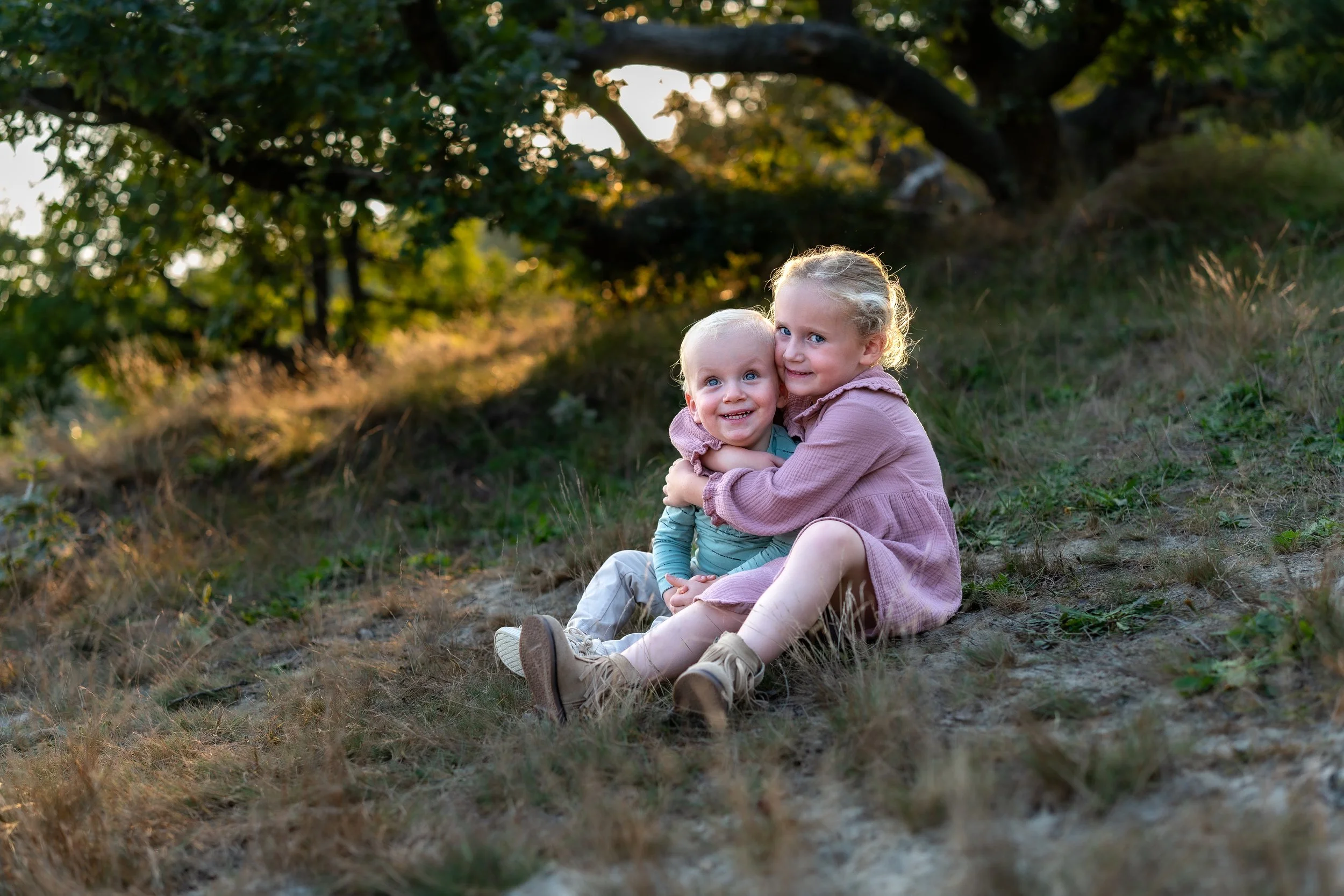 Broer en zusje samen knuffelen spontaan momentje in de heide Brabant