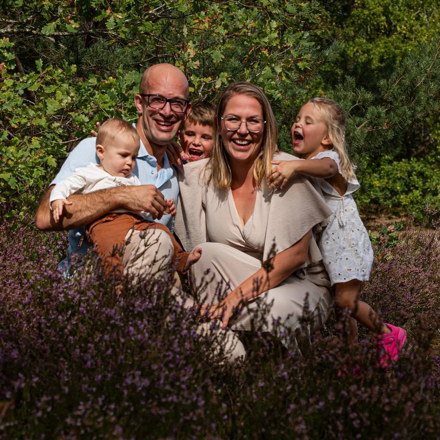 Gezinnen in een veld met bloemen, lachend en knuffelend.