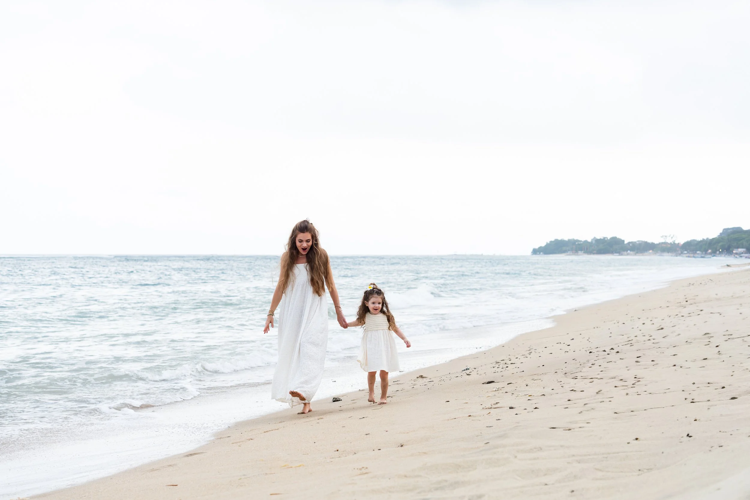 Moeder en dochter wandelen hand in hand op het strand in Zeeland