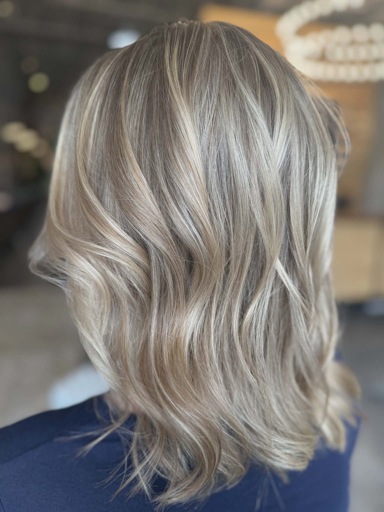 Blonde, wavy bob haircut on a person seen from the back.