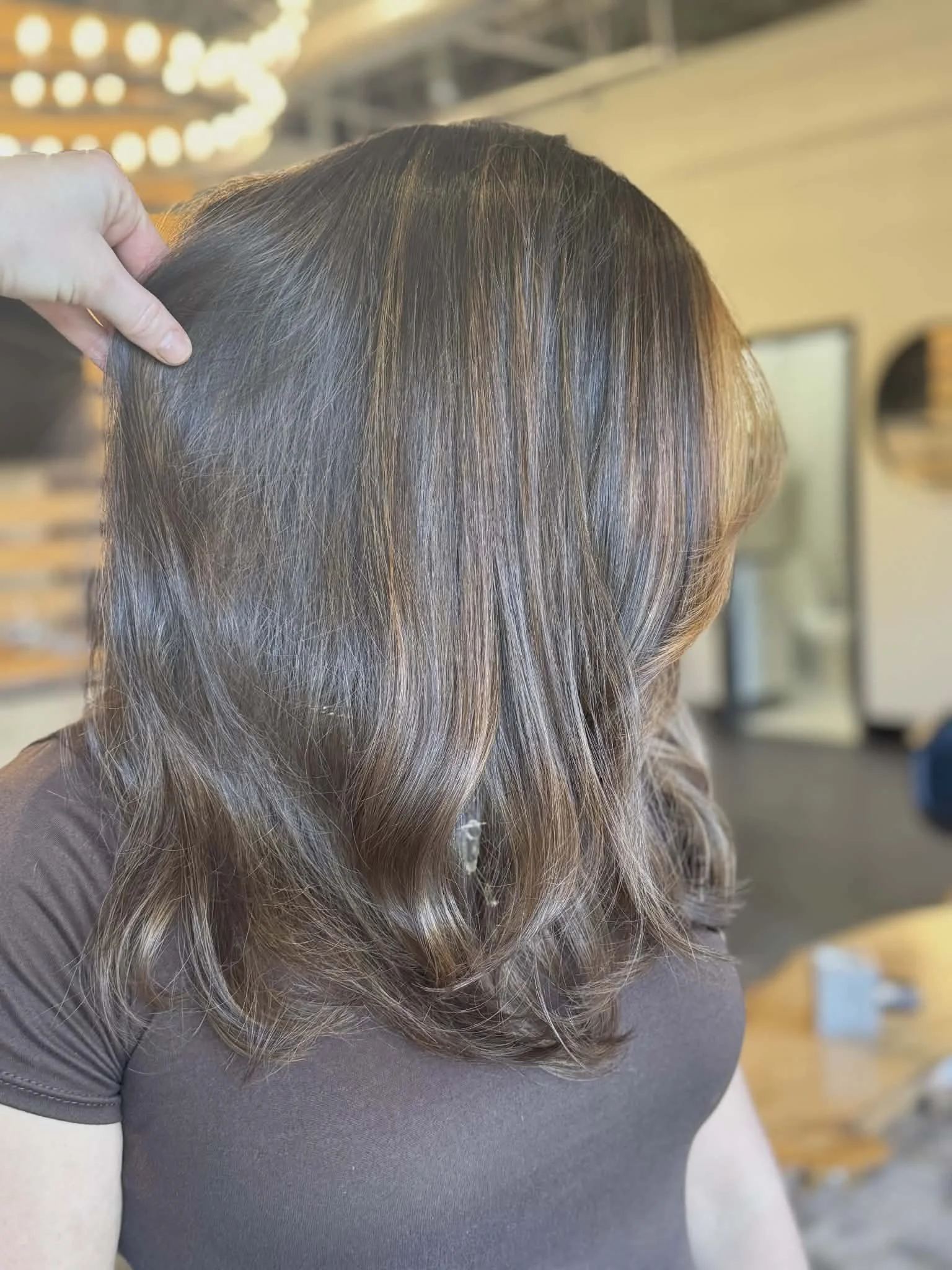 Side view of a woman with wavy, chestnut brown hair.