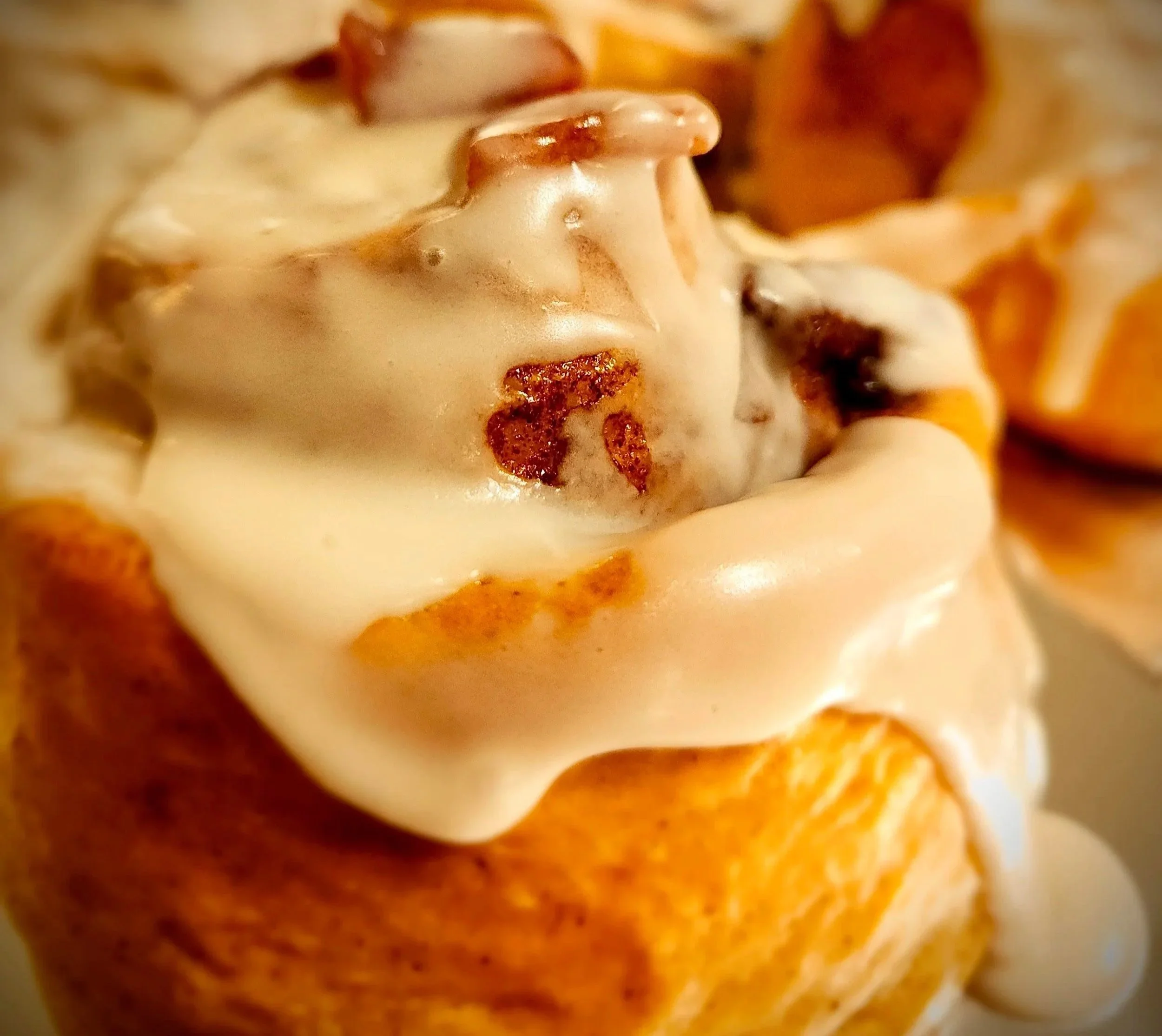 Close-up of a cinnamon roll topped with cream cheese frosting.