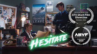 A young girl and a young man are in a bookstore or media store, with books and posters on the wall. The girl is seated at a counter, and the young man is standing in front of her, holding a piece of paper. There are logos and text overlay on the image, including 'Hesitate' in green neon styling, and various film festival badges and banners, indicating an ATX Short Film Showcase event in October 2021.