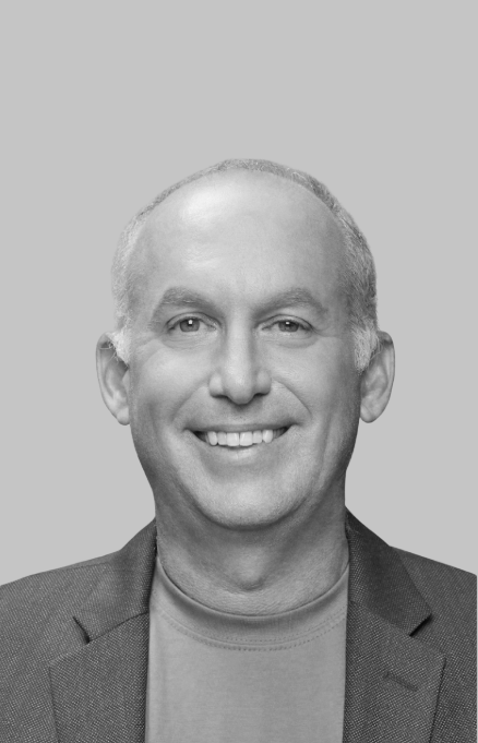 Black and white portrait of a smiling man in a blazer with a light-colored shirt against a plain background.