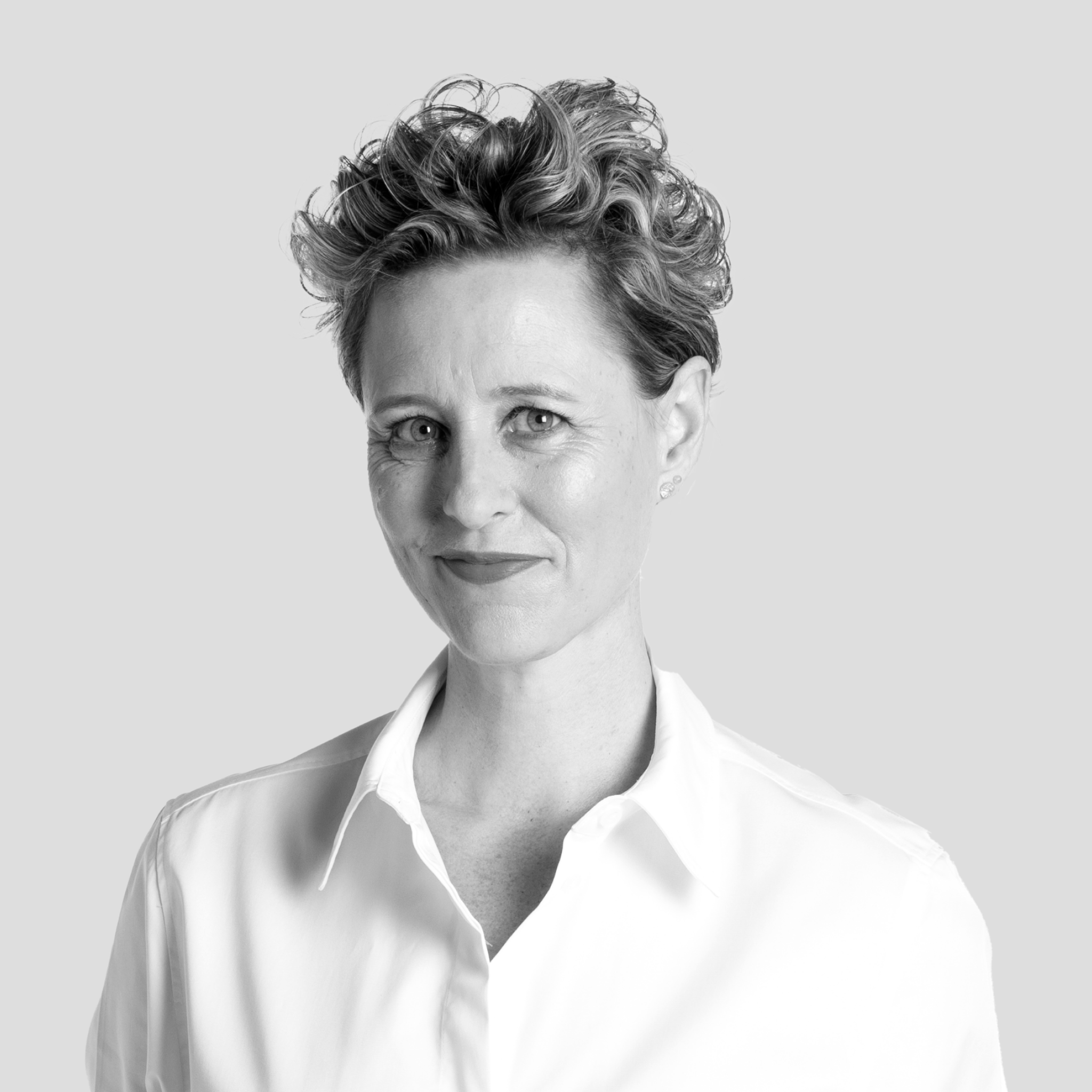 Black and white portrait of a woman with short, curly hair wearing a collared shirt, smiling subtly.