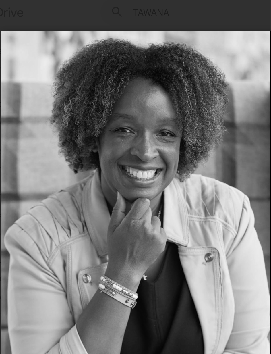Black and white portrait of a woman smiling, with curly hair, wearing a light-colored jacket and bracelets.