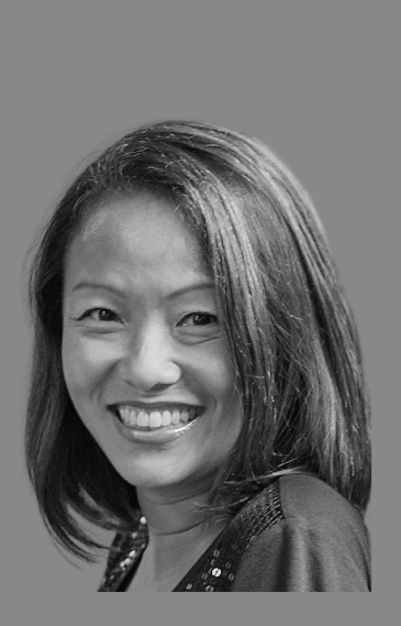 A smiling woman with shoulder-length hair looking at the camera, in black and white.