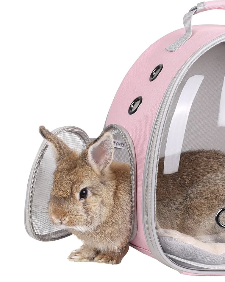 A small brown rabbit inside a pink pet carrier with a mesh door, sitting outside with one ear up.