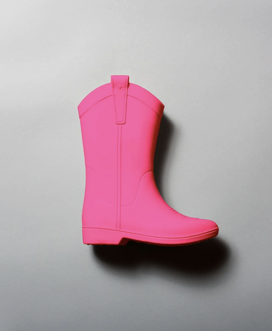 A pink rubber rain boot on a light gray surface.