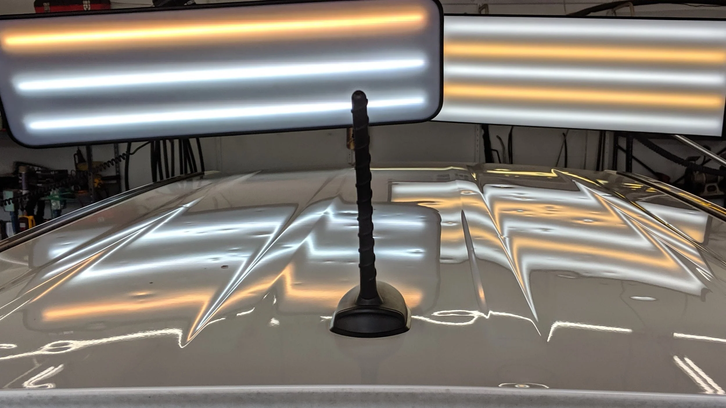 Car with two illuminated LED light bars mounted on the roof, one larger and one smaller, reflecting off the shiny surface of the vehicle.