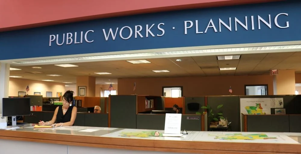 Reception area at a public works and planning government office with staff working at desks.