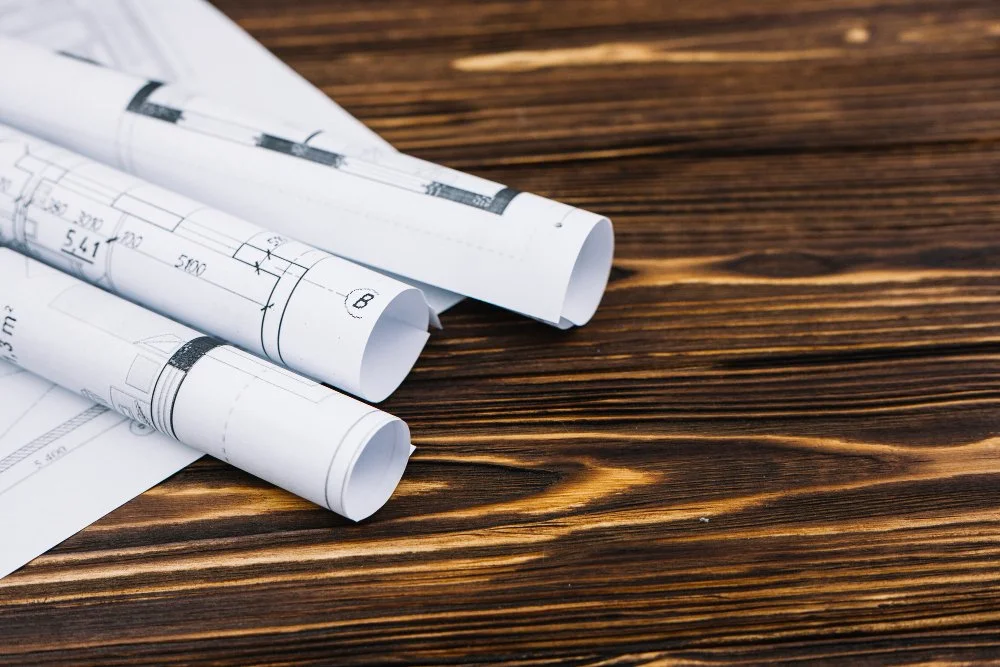 Rolled blueprints and drawings on a wooden surface.