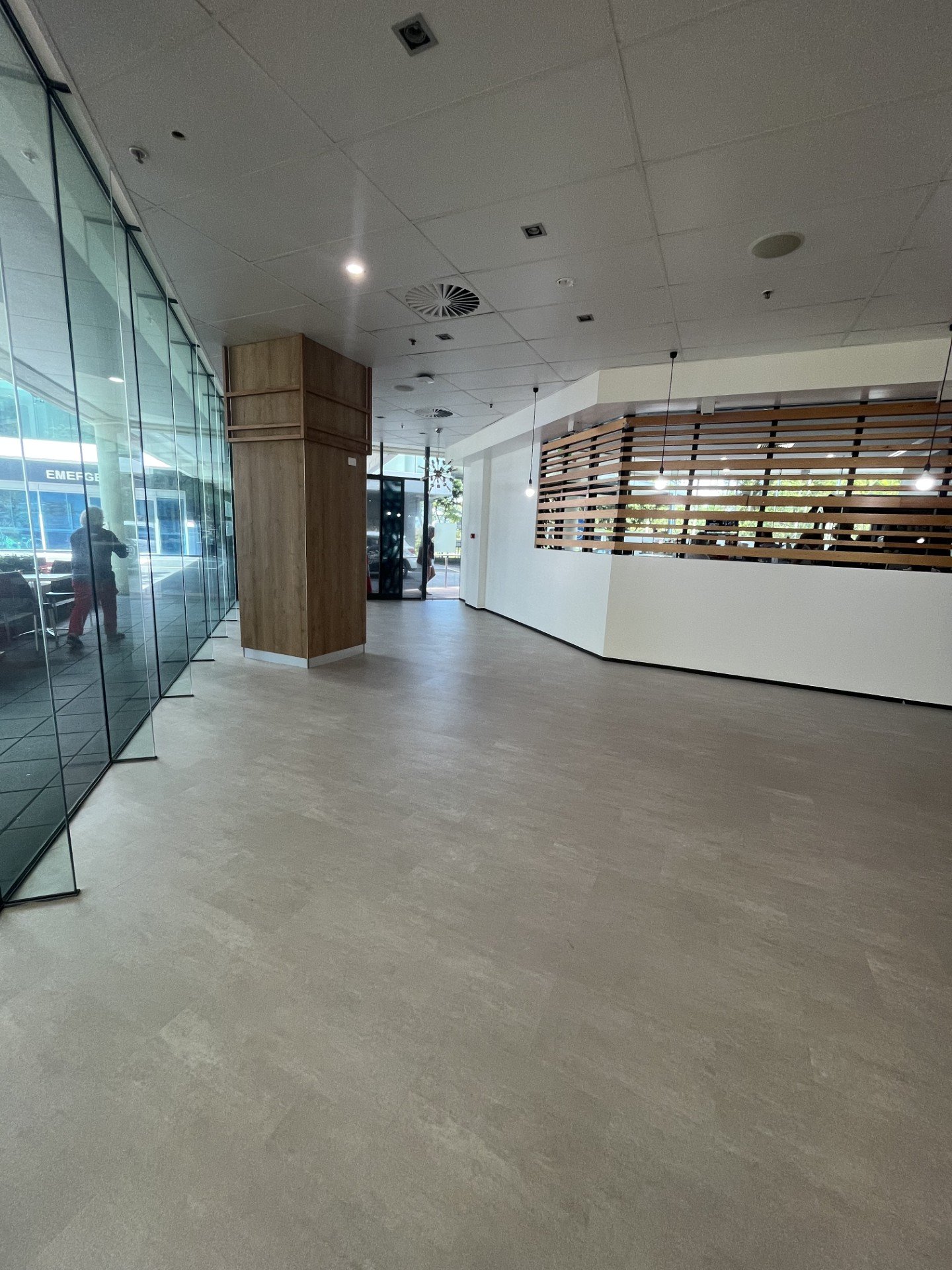 Interior of a modern building lobby with large glass windows, wooden accents, and pendant lighting.
