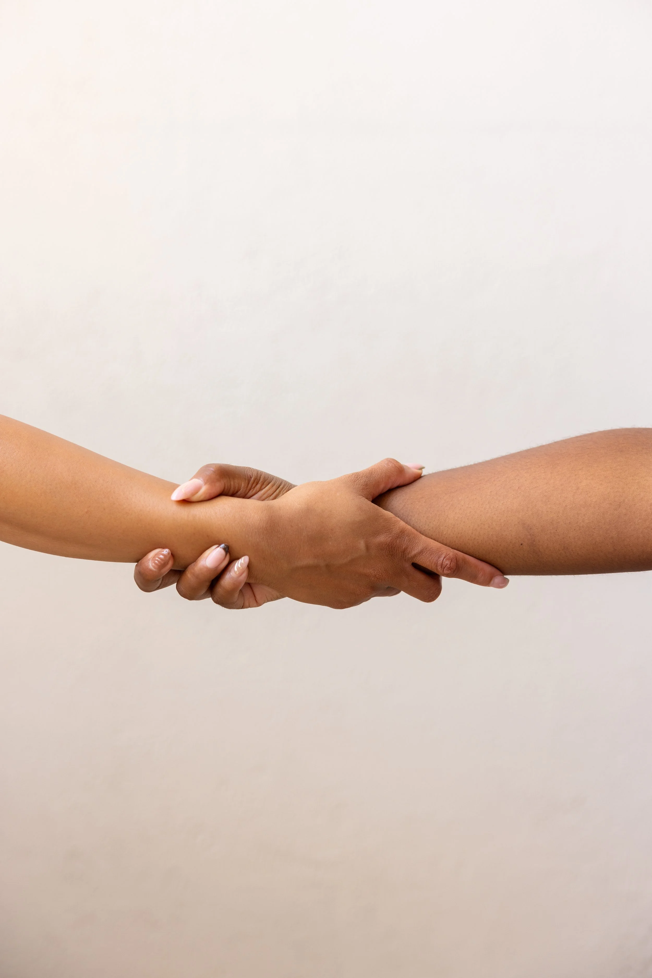 Two people holding hands against a plain white background.