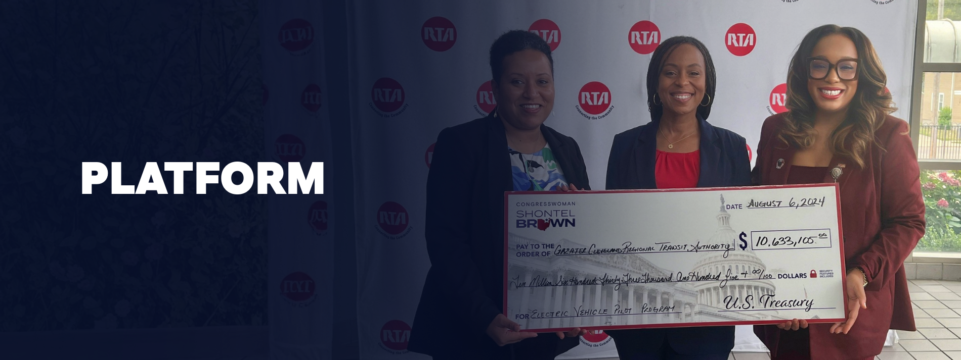 Three women standing together, one holding a large ceremonial check made out to the Greater Cleveland Regional Transit Authority, dated August 6, 2024, for $10,633.105, with a background featuring RTA logos and a window with greenery outside.