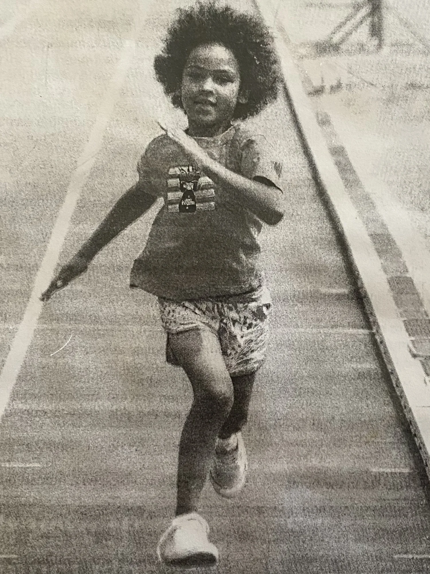 A nostalgic black and white childhood photograph of Sené Maluwapi running, capturing the 'old soul' energy and early movement that defines her journey as an international model.