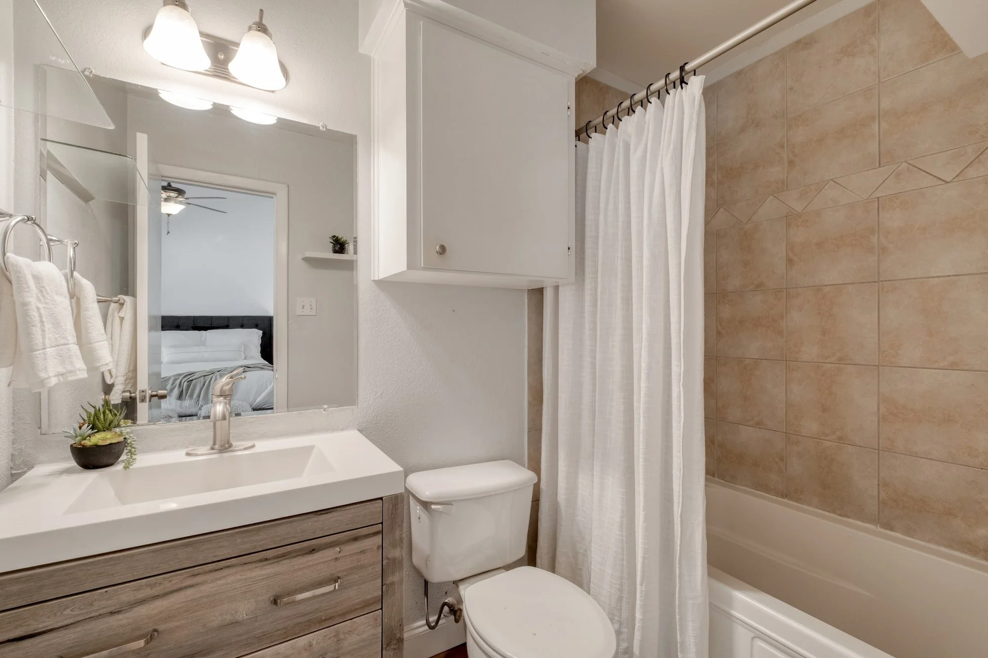 Updated bathroom with modern vanity and tiled tub surround