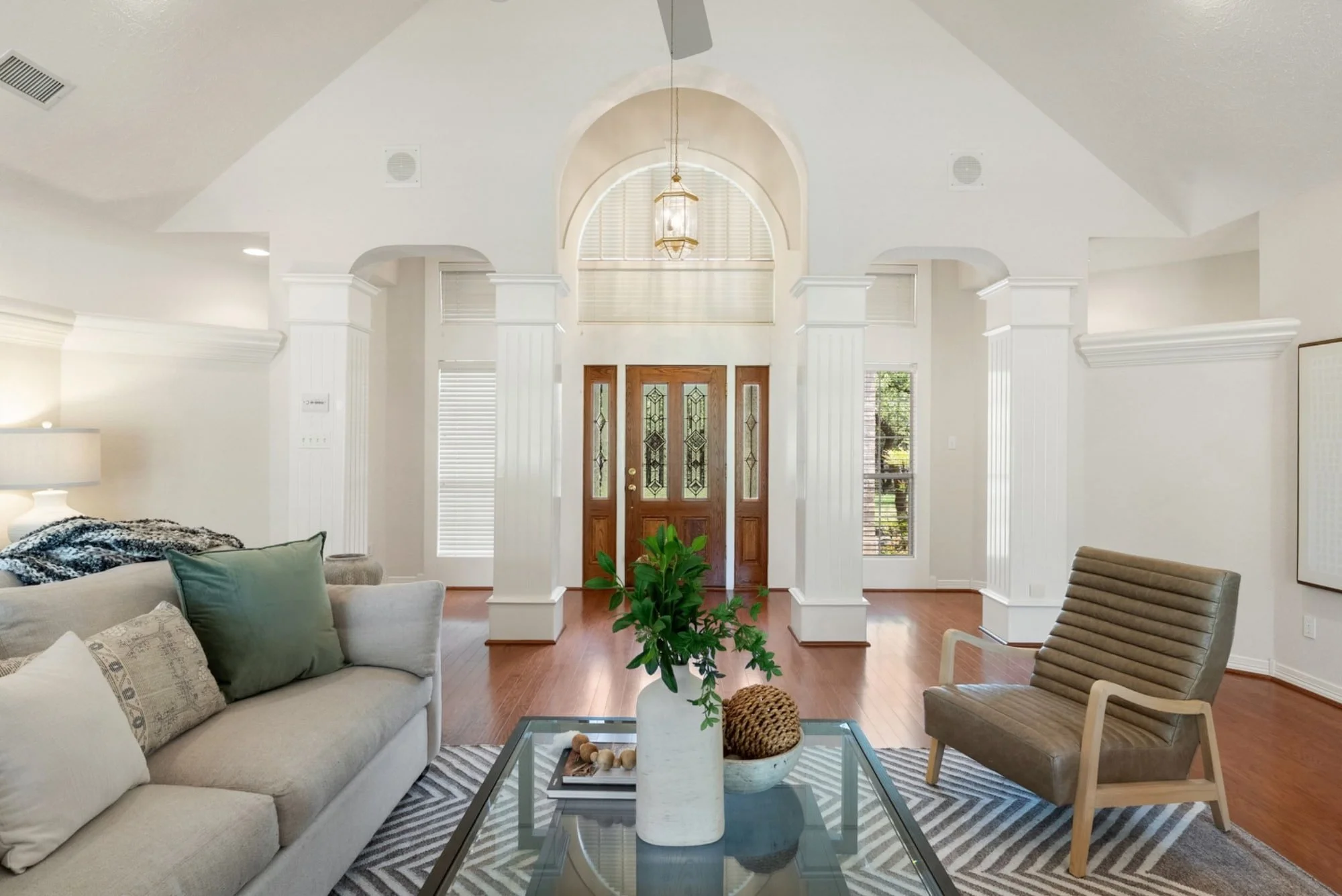 Living room with vaulted ceilings, hardwood floors, and a view of the front entry.