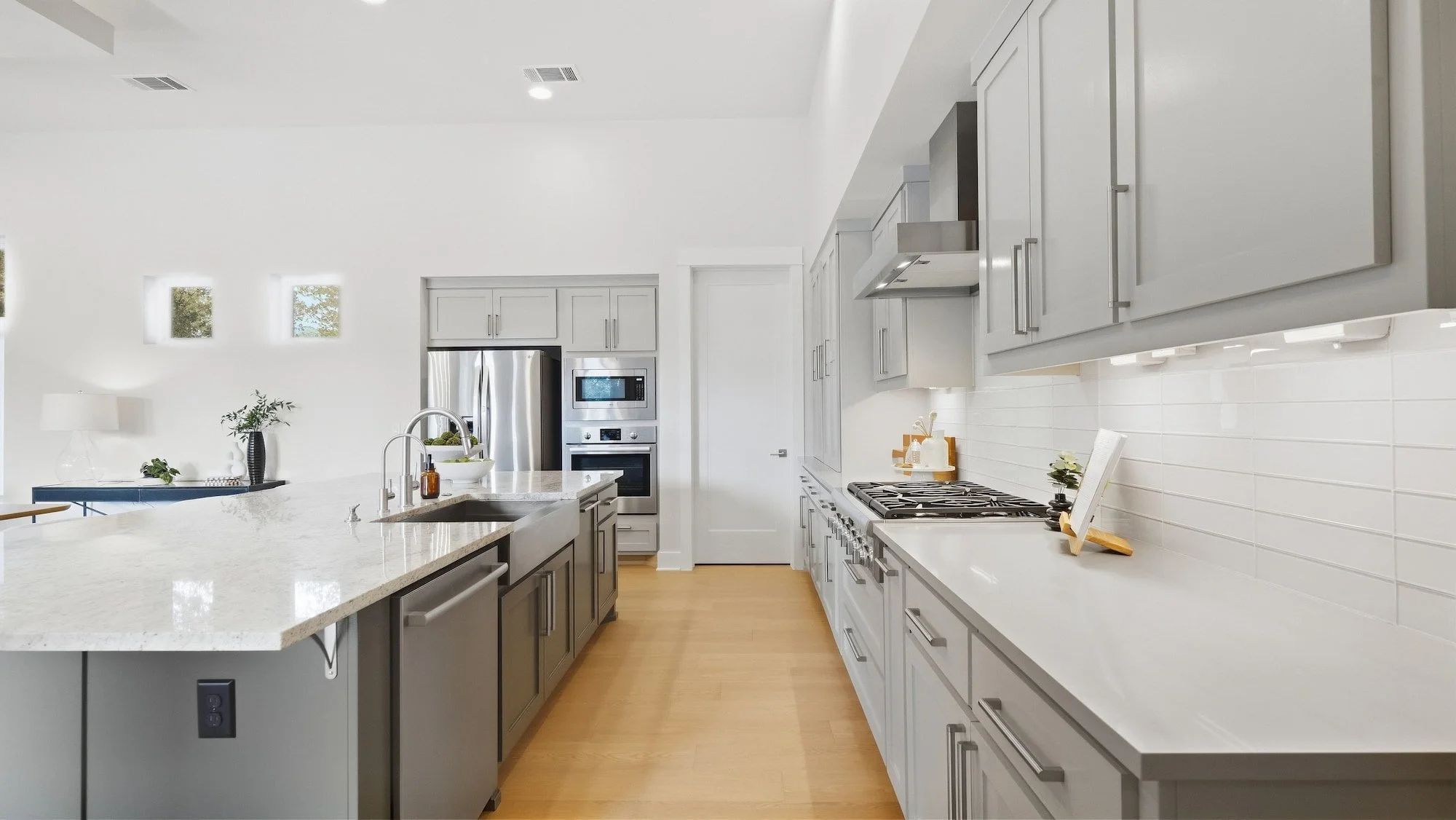 Kitchen staging with a granite island, gray shaker cabinets, and a gas range with cookbook display.
