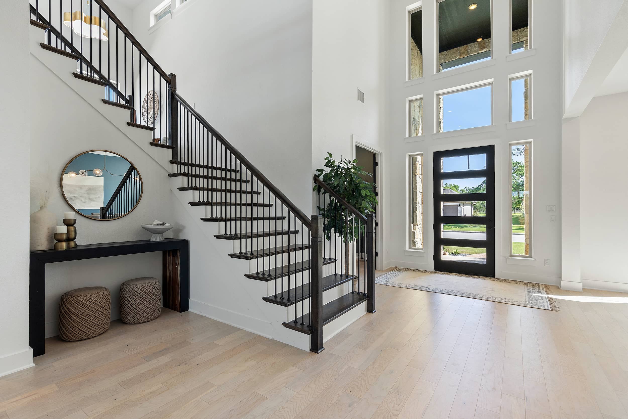 Bright modern foyer with wood flooring, metal railings, statement door, high ceilings in Austin real estate staging style