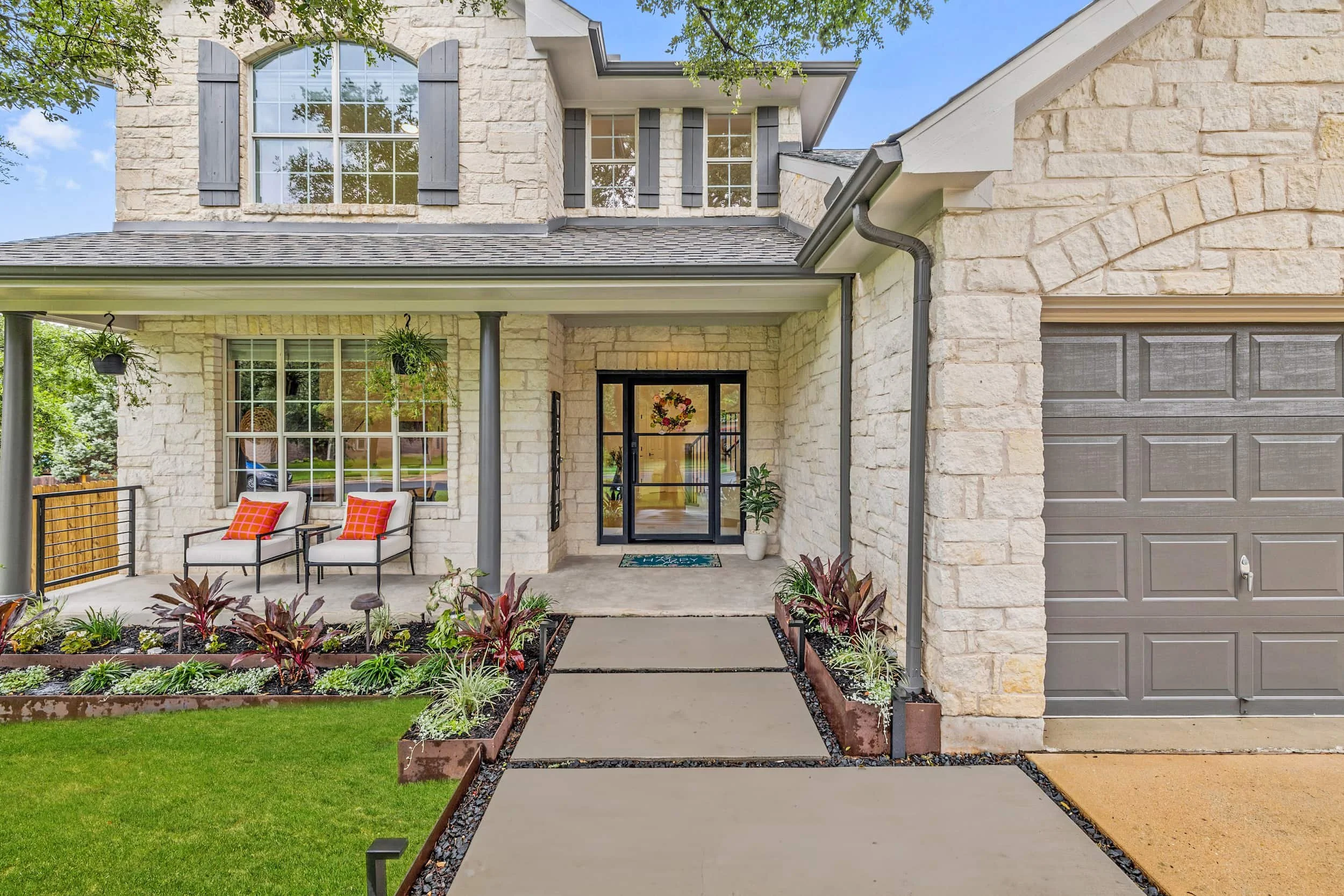Inviting home exterior with a covered front porch, outdoor seating, landscaped entry walkway, and attached garage.
