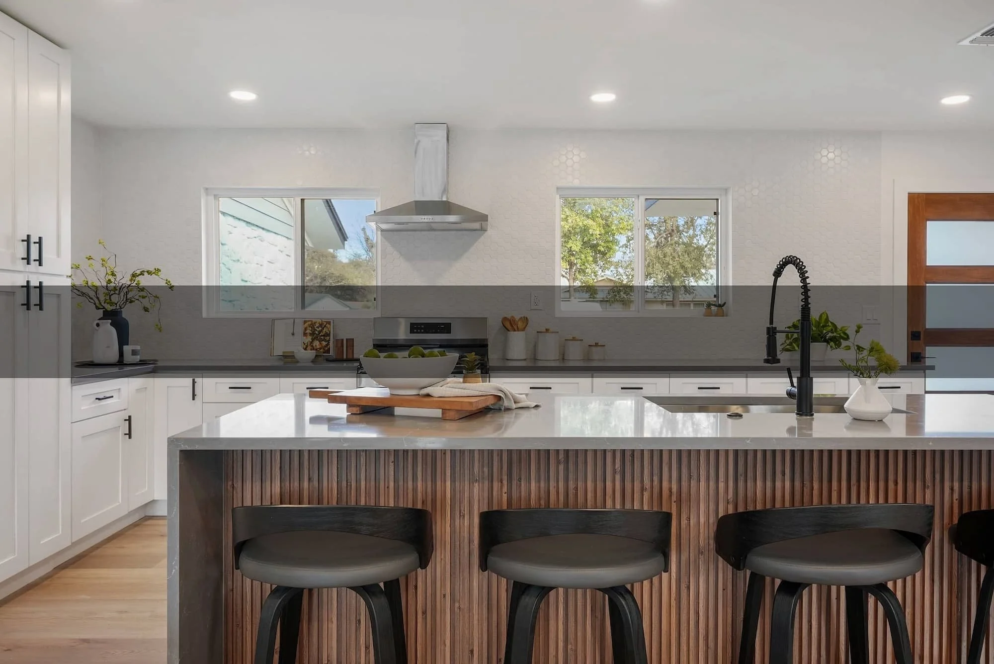 Elegant kitchen with waterfall quartz, fluted wood paneling, statement faucet, and curated staging.