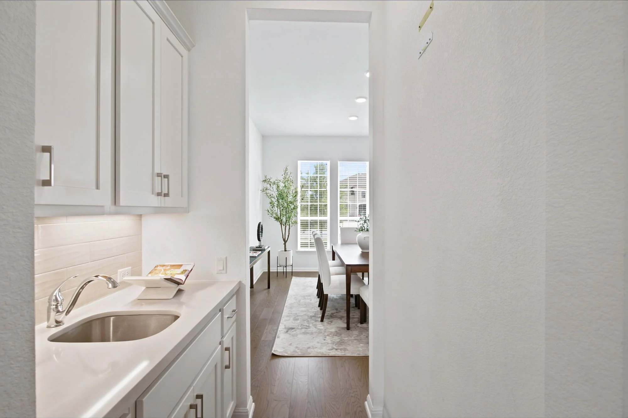 Crisp white cabinetry lines the pantry hall, guiding the eye toward the dining room beyond.