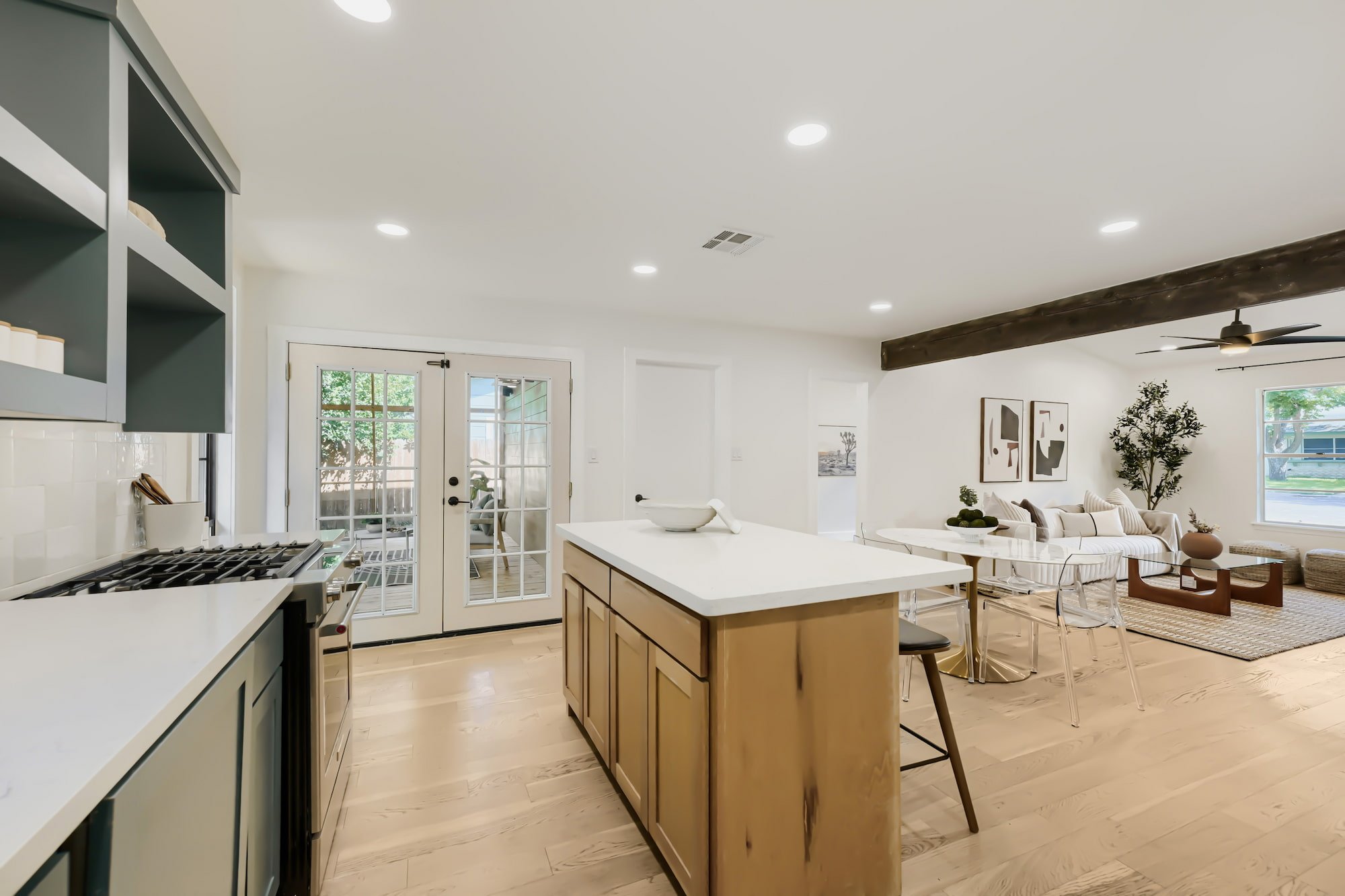 Staged kitchen with a wood island and gas range, opening to the dining and living area and out to a screened porch.