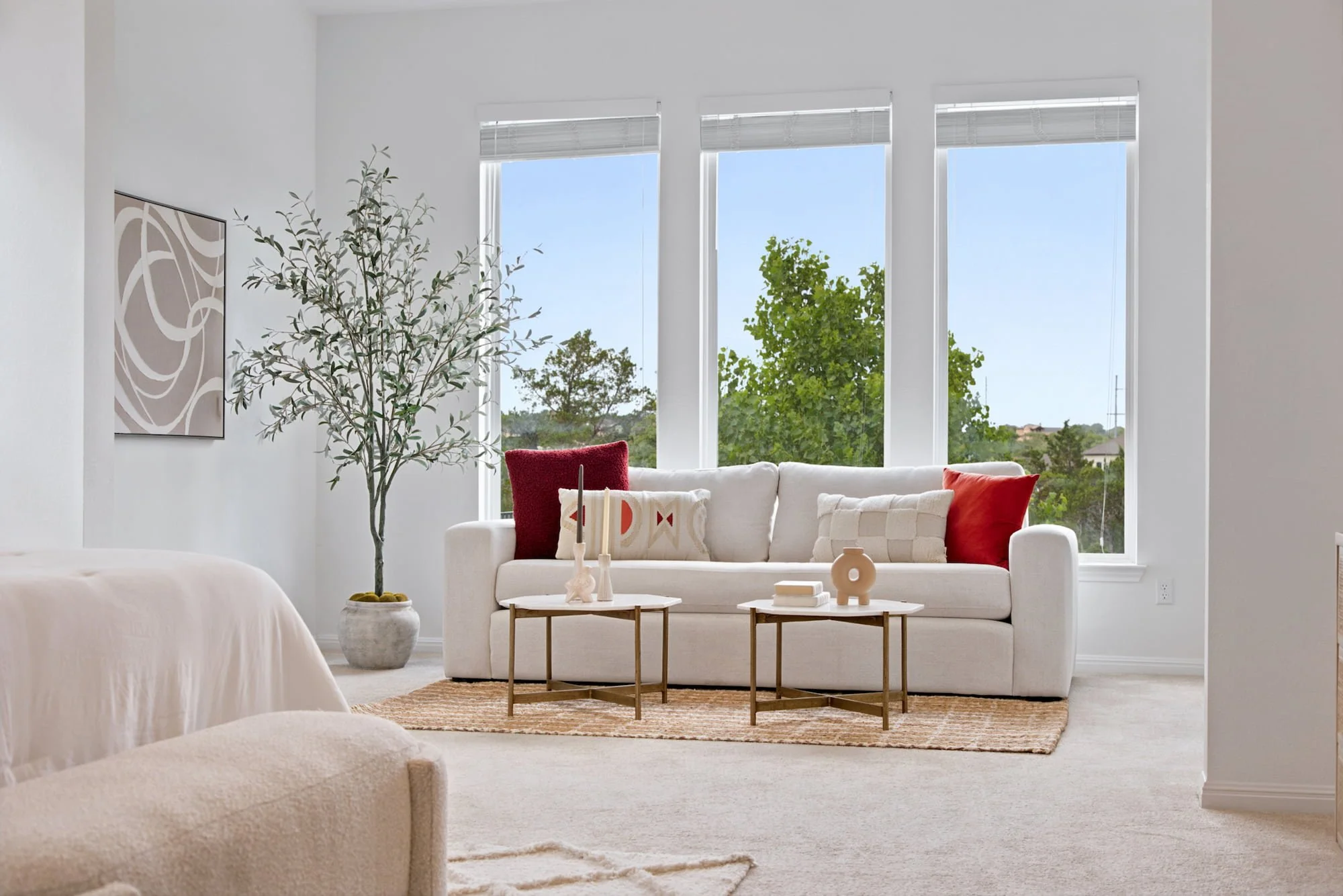 A cream sofa styled with red accent pillows sits beneath tall windows.