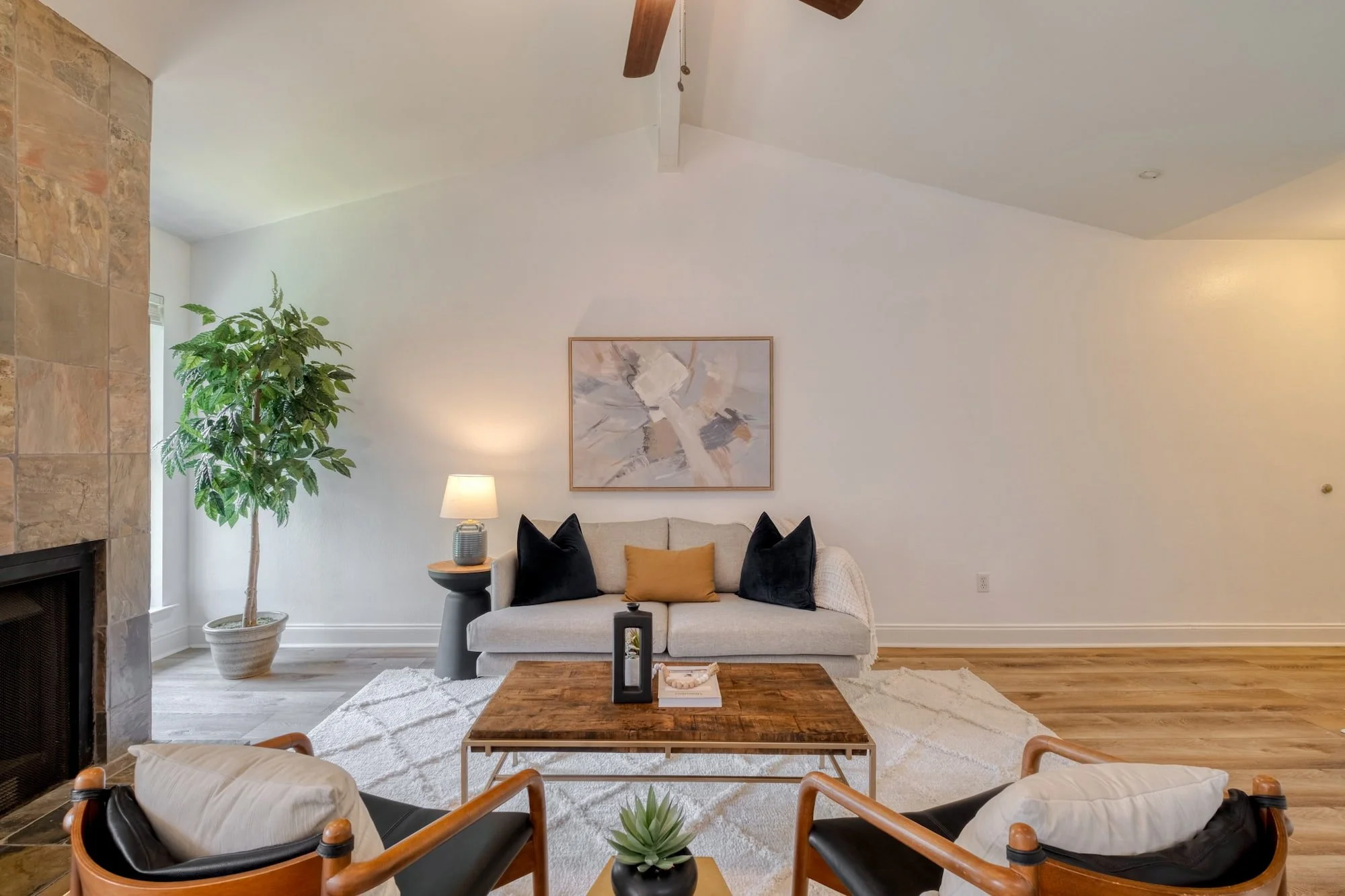 Staged living room in North Loop, Austin with vaulted ceilings, a stone fireplace, and modern furnishings.