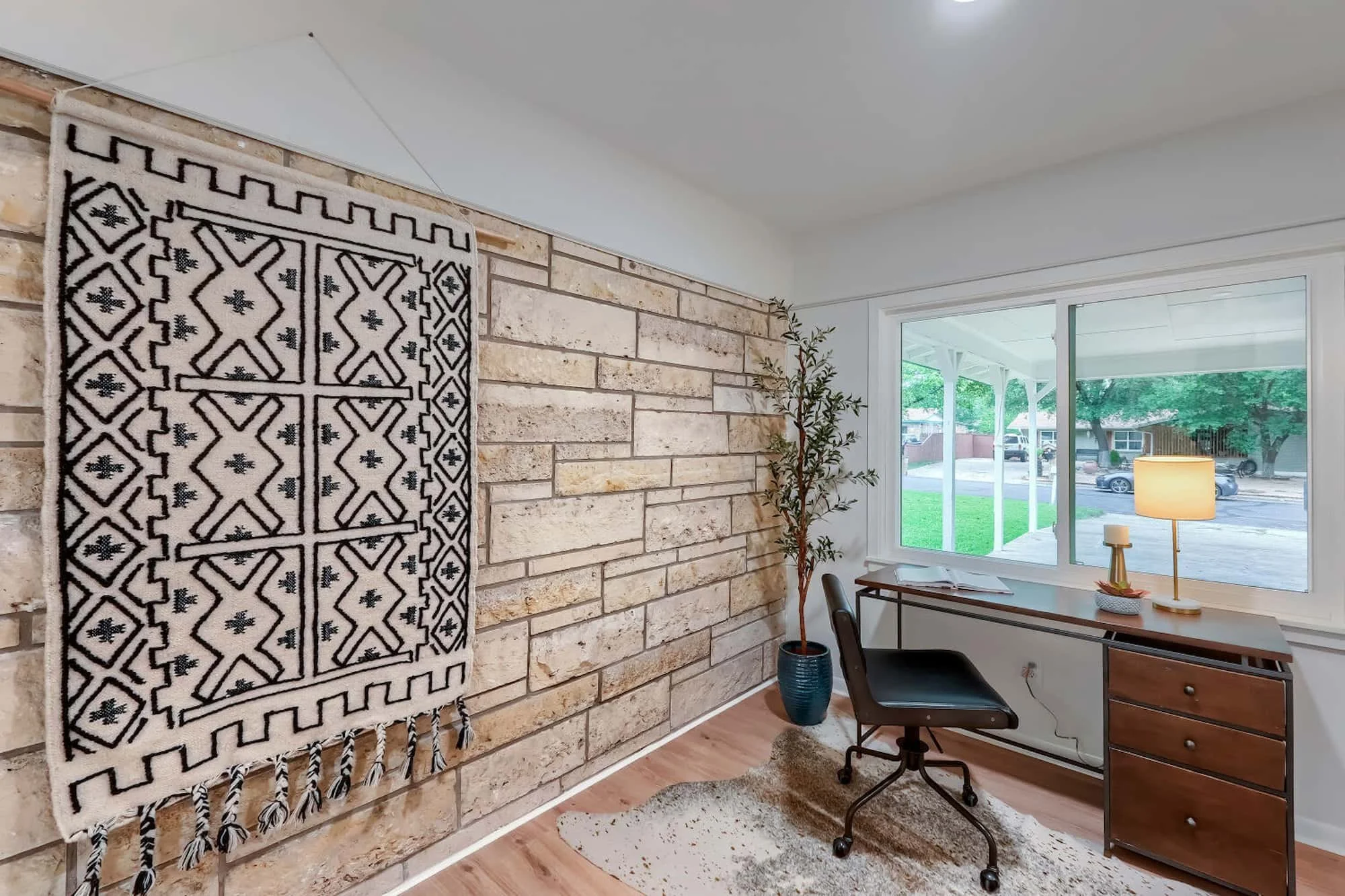 Home office with a striking stone accent wall and natural light.