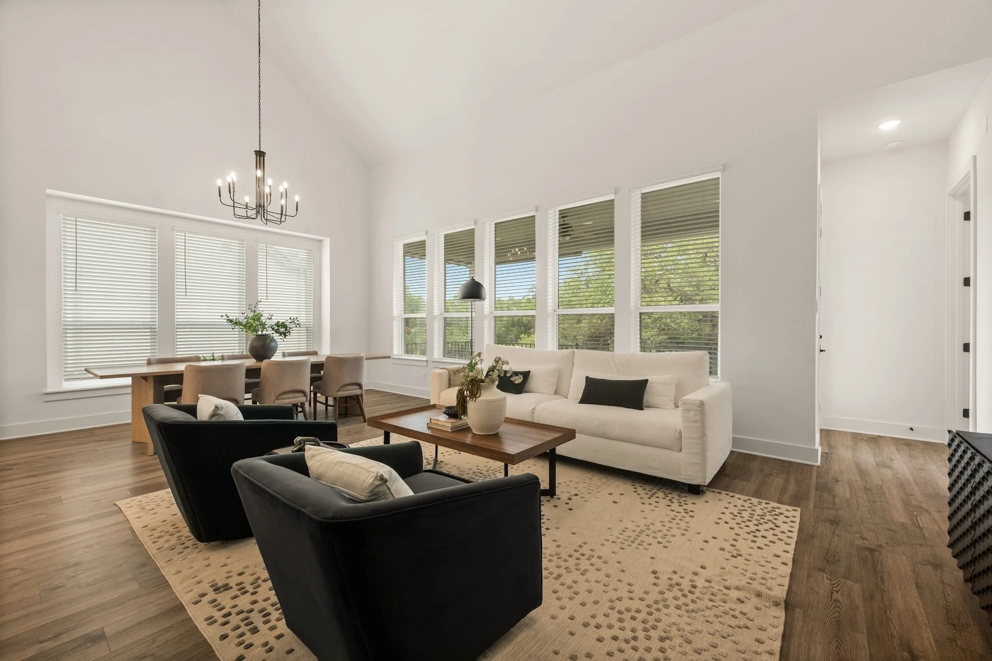 Bright open living area in Leander, Texas, with vaulted ceilings, oversized windows, and adjacent dining space