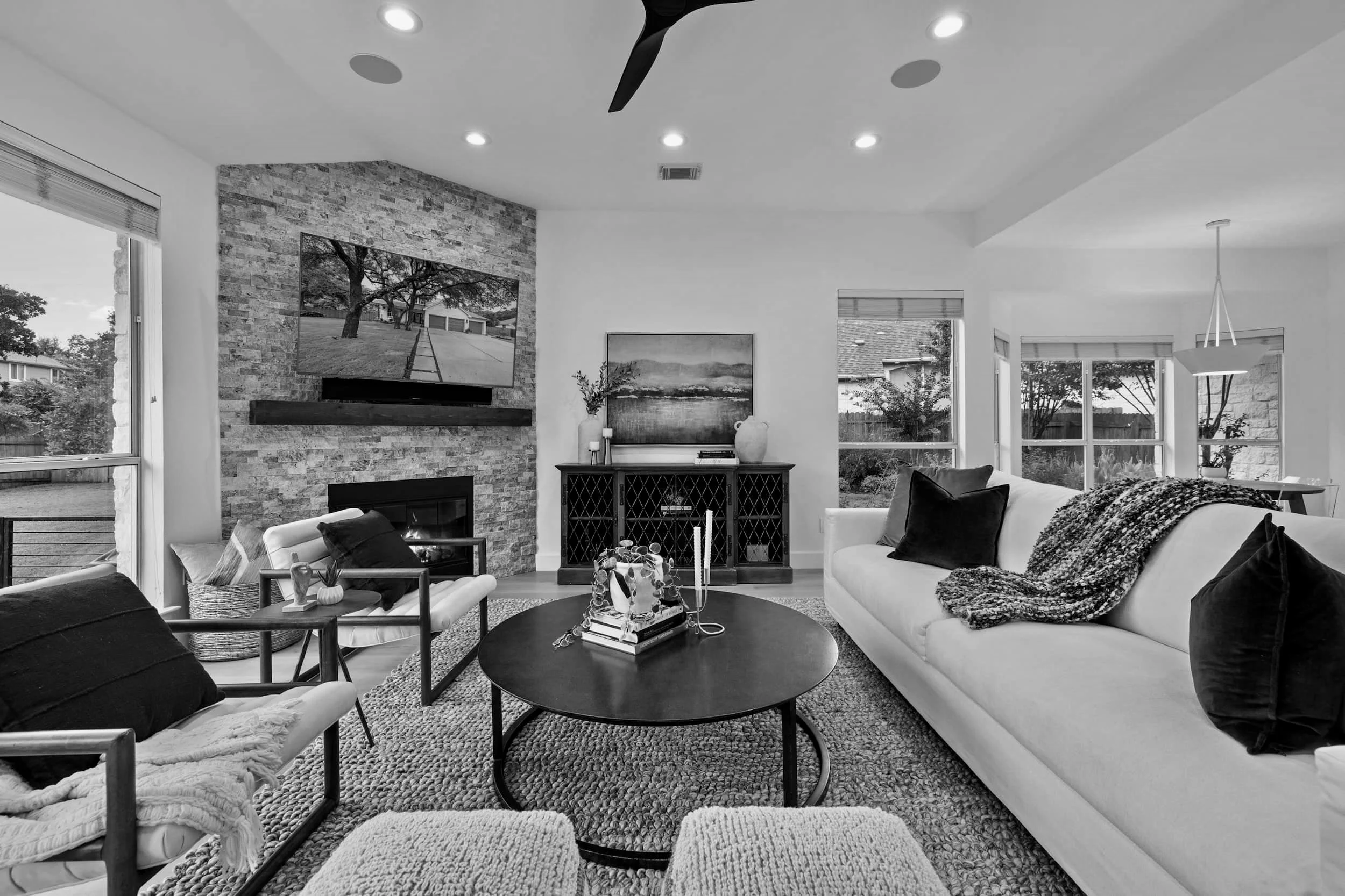 Staged living room with stone fireplace, sofa, and ceiling fan in Austin, TX