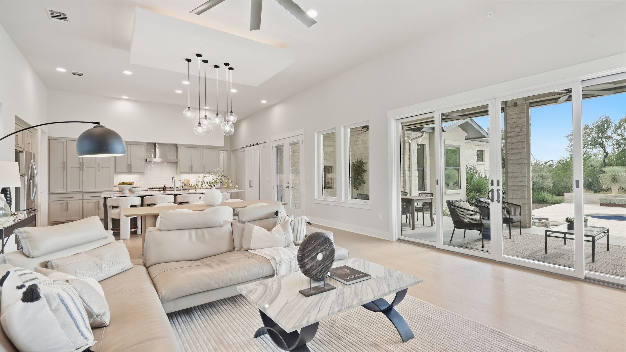 Living room staged with a cream sectional, opening through sliding glass doors to a covered patio.