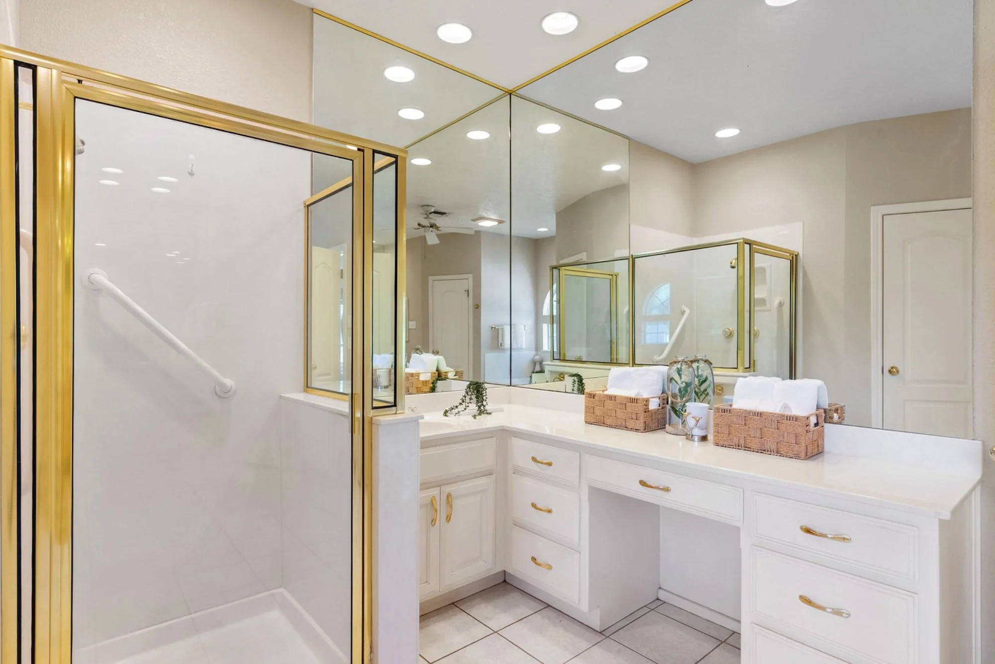 Primary bathroom with a walk-in shower, built-in vanity, and wall-to-wall mirrors.