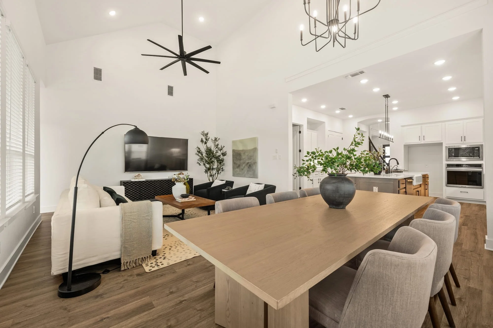Open-concept dining and living area with soaring ceilings, designer lighting, and seamless flow to the chef’s kitchen