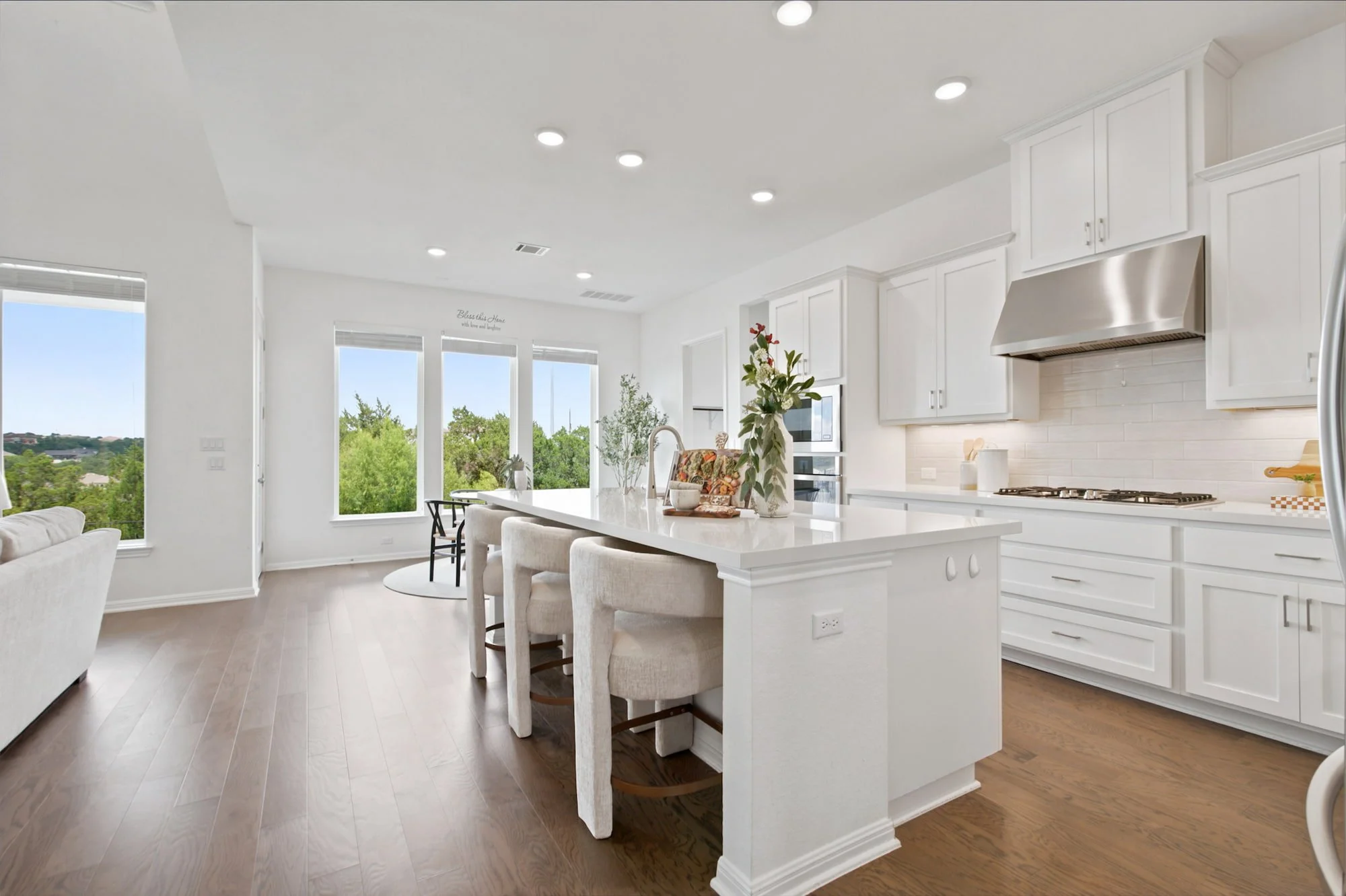 A long white island with counter stools anchors the open kitchen and living space.