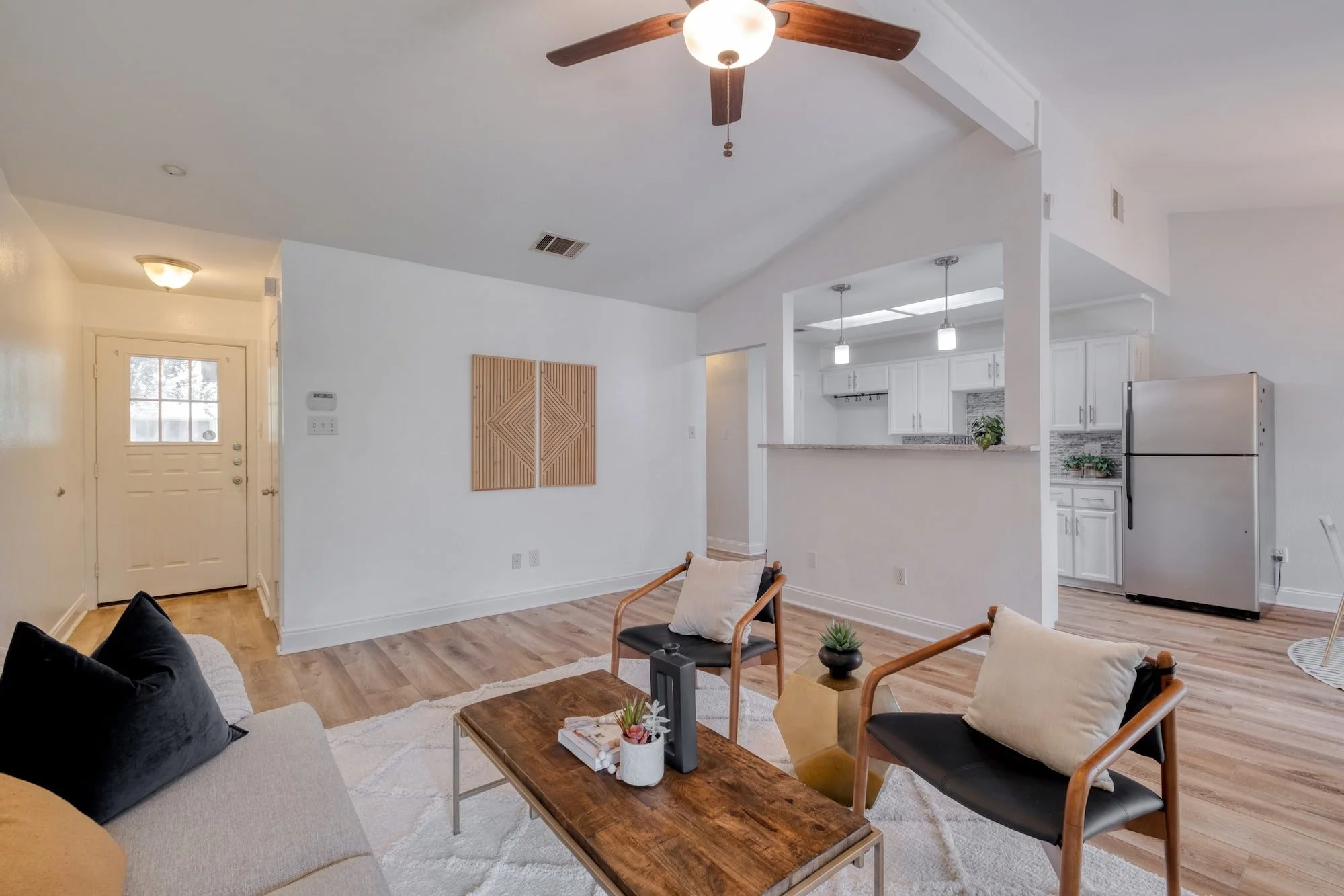 Open-concept living area with vaulted ceilings, modern staging, and a bright kitchen connection.