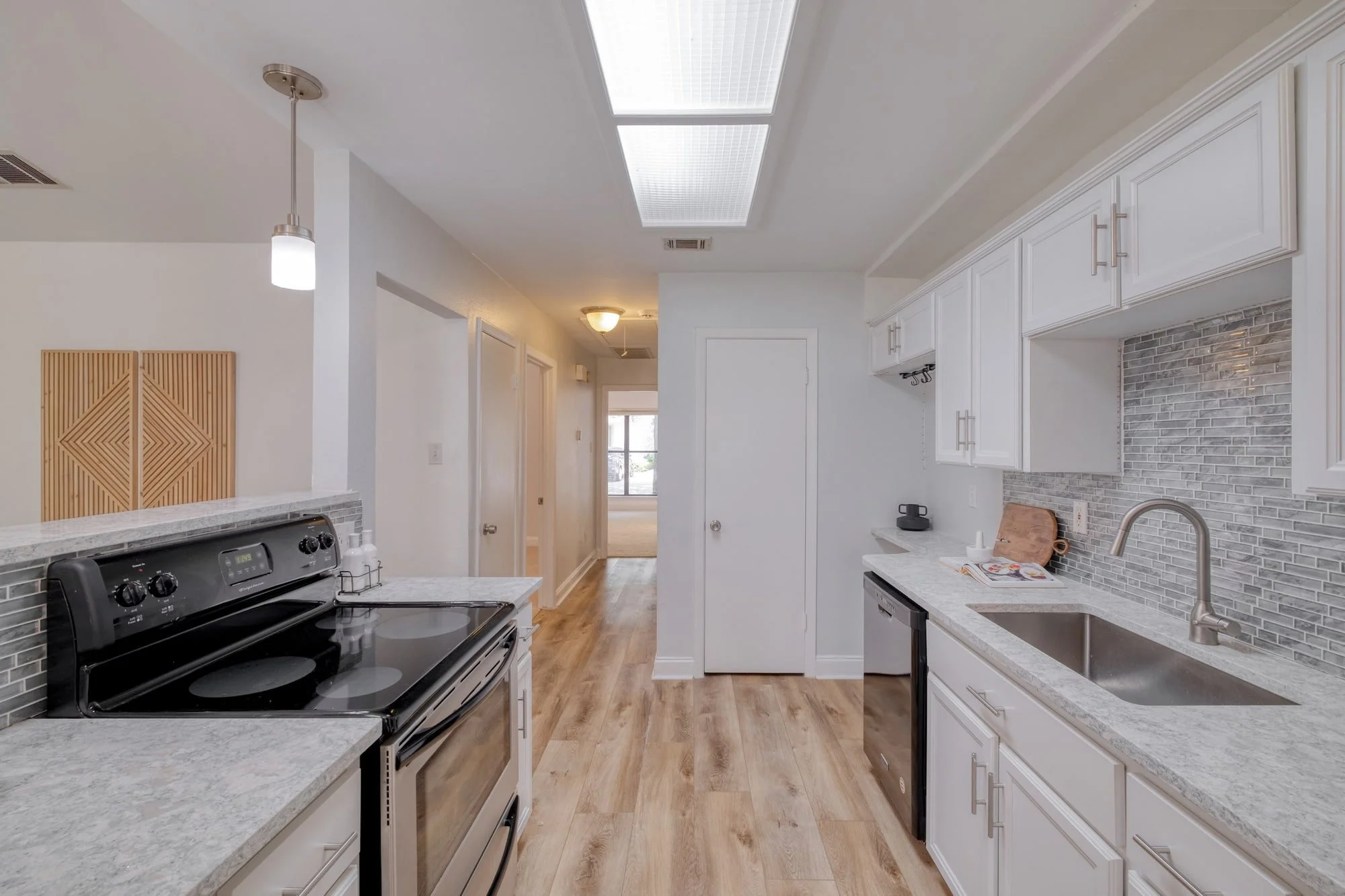 Galley-style kitchen in Central Austin with white cabinetry and stainless steel appliances