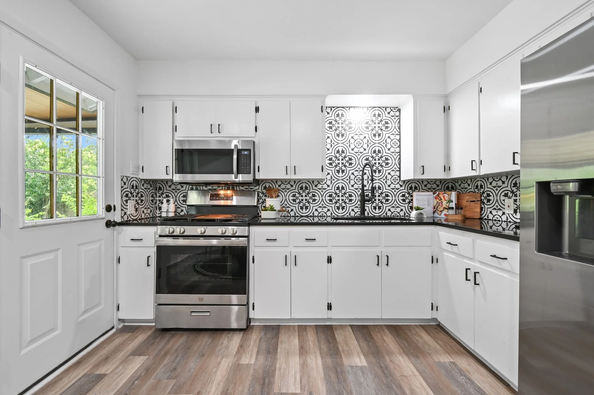 Black countertops and patterned tile give this kitchen a graphic, modern feel near the back door.