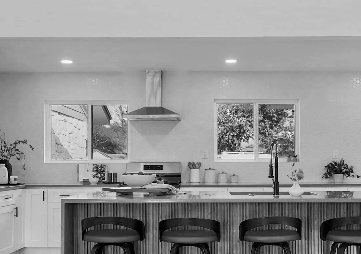 Staged kitchen with island, bar stools, and large windows