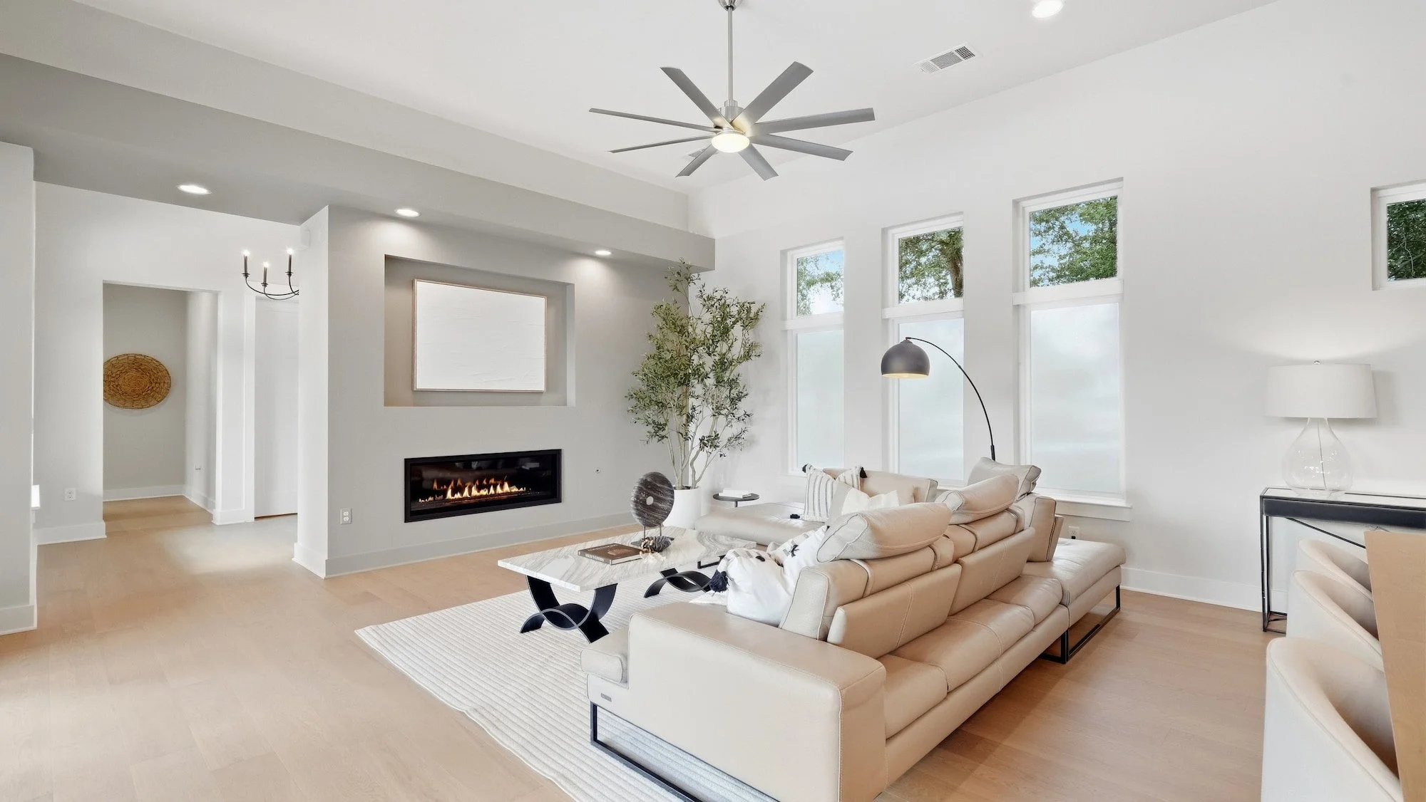 Living room staged with a cream leather sectional and marble coffee table facing a linear fireplace.