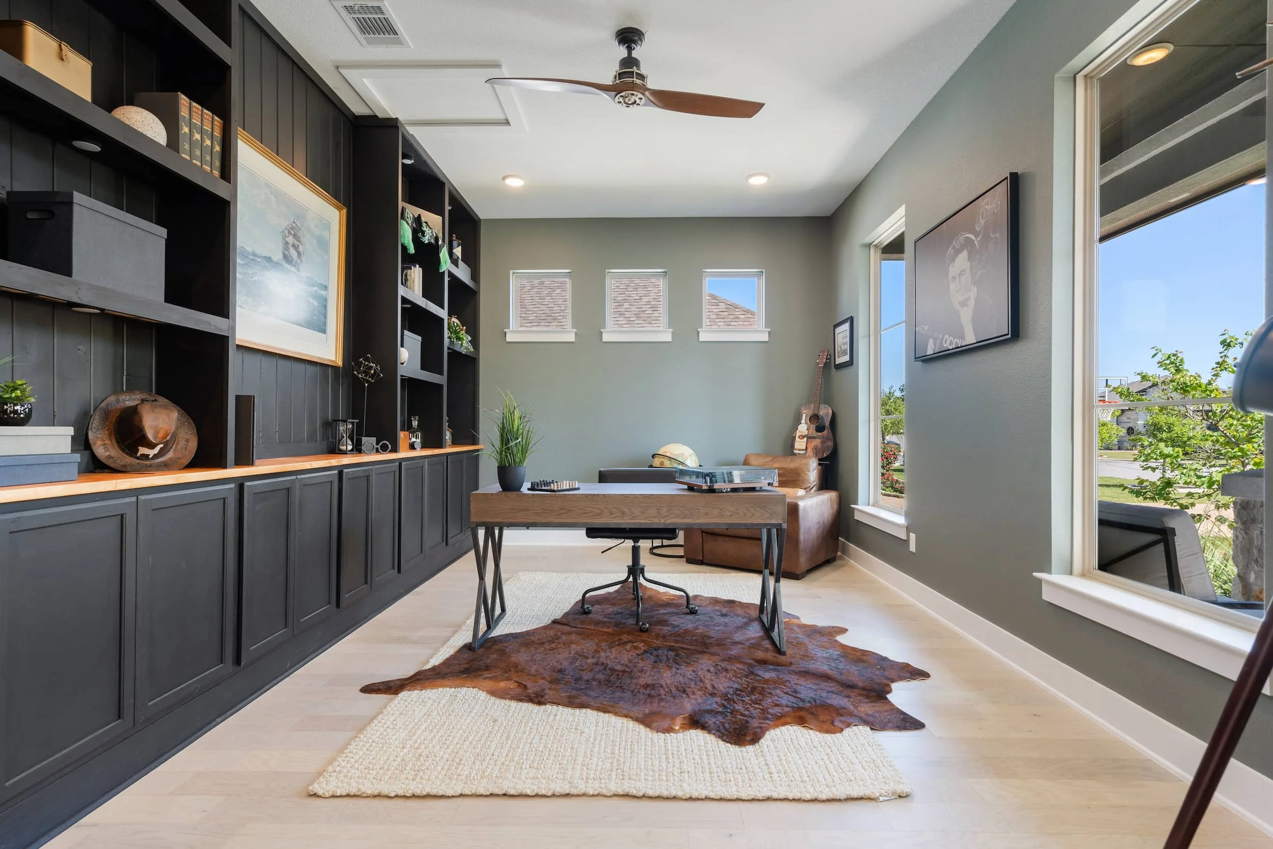 Professionally staged Austin study with dark cabinetry, shelving, natural light, and minimalist decor.