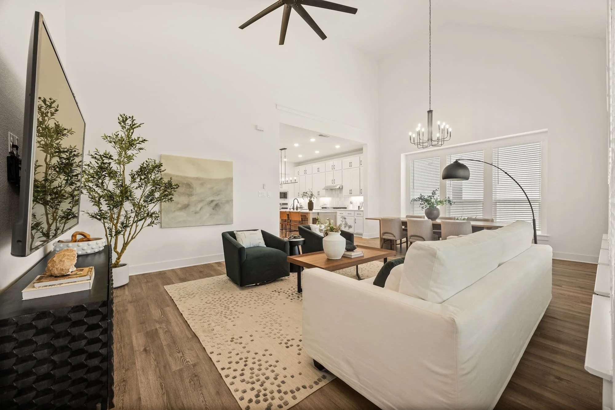 Open-concept living and dining area with soaring ceilings, designer lighting, and seamless kitchen connection
