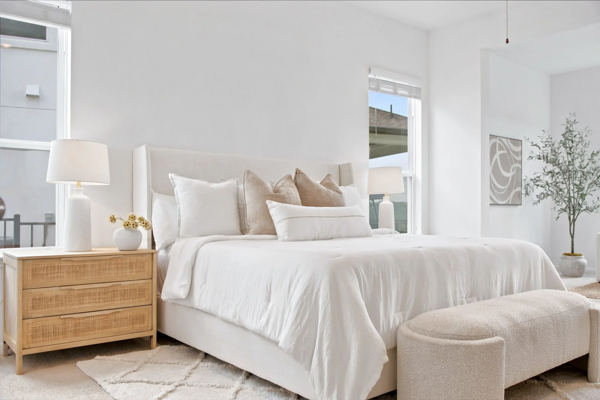 Soft neutral pillows and cane nightstands dress the primary bedroom's bed.